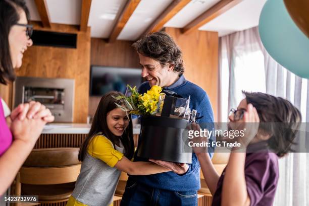 father receiving a gift box from family at home - happy birthday flowers images stock pictures, royalty-free photos & images