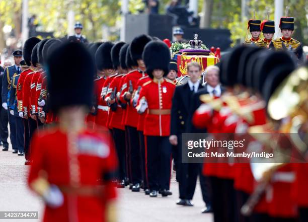 Queen Elizabeth II's coffin, draped in the Royal Standard and bearing the Imperial State Crown, is transported on a gun carriage from Buckingham...