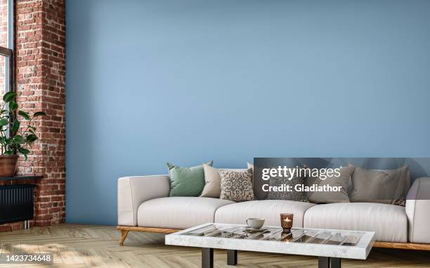 empty nostalgic retro living room with beige sofa, colored cushions, coffee table, and decoration (potted plant) in front of a colored wall and partly ruined brick wall - table brick wall wood stockfoto's en -beelden