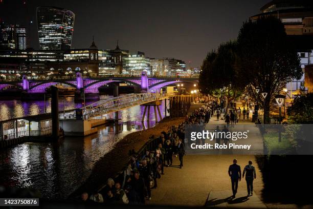 People stand in line along Southbank as tens of thousands join queues to see Queen Elizabeth II lying in state at Westminster Hall on September 14,...