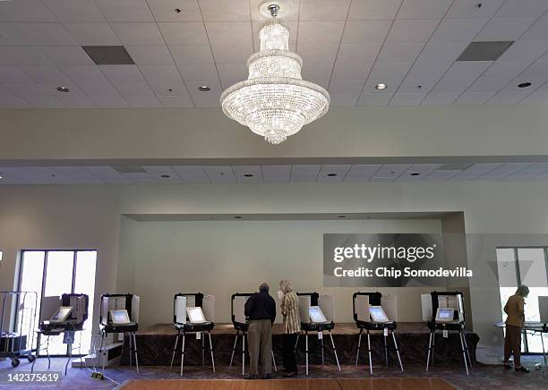 Polling place worker assists a voter with a digital voting machine during the presidential primary election at Saints Peter & Paul Antiochian...