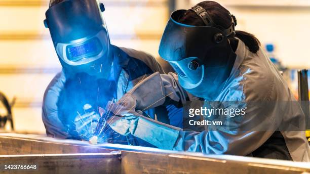 workers welding metal material - lasser stockfoto's en -beelden