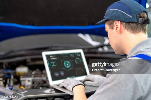 tuning up for the best performance. the car's electronic programming uses the laptop to link and checks the data in the engine by monitoring the digitization display to keep and tune the best performance of the engine in the garage or car repair shop. - auto repair shop foto e immagini stock