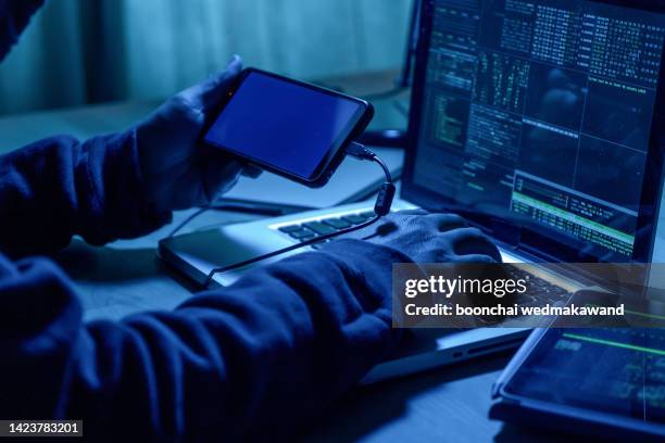 hacker with mobile phone and computer in a dark room. cyber crime  concept. - espía fotografías e imágenes de stock