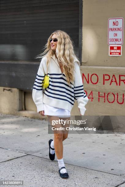 Emili Sindlev wearing stripped jumper with zipper, white skirt, white socks, yellow bag outside Cos on September 13, 2022 in New York City.