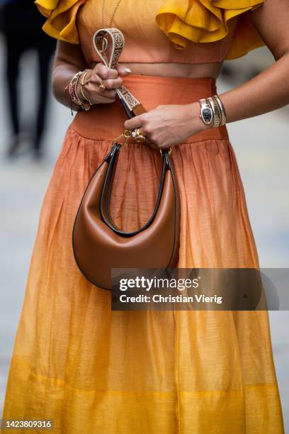 Nina Suess wearing brown bag, orange yellow shaded skirt, ruffled blouse outside Cos on September 13, 2022 in New York City.