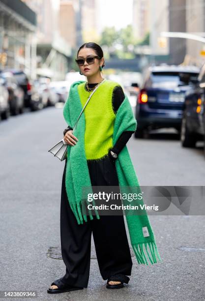 Guest wearing green pull under, scarf, black pants outside Cos on September 13, 2022 in New York City.