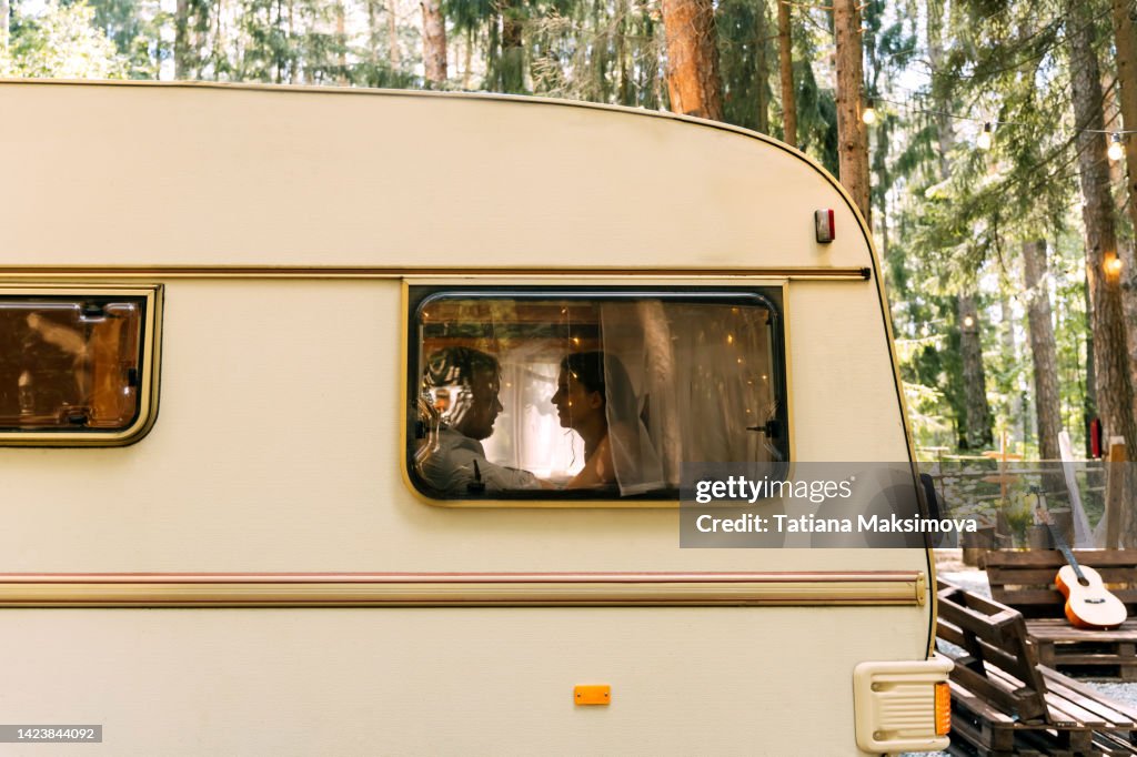 A young couple in love in a camper trailer on a summer day.
