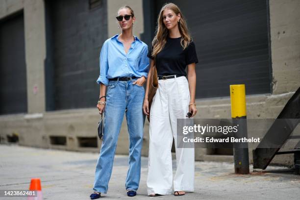 Guest wears silver earrings, a baby blue cotton shirt, a black shiny leather belt, blue faded denim large pants, silver rings, a black shiny leather...