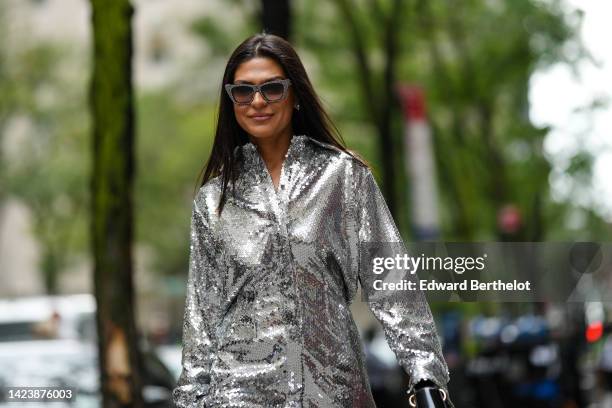 Guest wears black and rhinestones sunglasses, white pearls earrings, a silver embroidered sequined long sleeves / shirt neck / long sleeves / long...