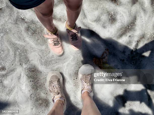 pov of an adult and child looking down at wet legs and footwear at an outdoor foam party at a summer street festival. - pov shoes ストックフォトと画像