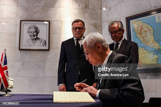 Malaysia Prime Minister Ismail Sabri Yaakob writes in a condolence book for the late Queen Elizabeth II accompany by Excellency Charles Hay and...