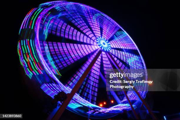 ferris wheel in motion at night - im kreis drehen stock-fotos und bilder