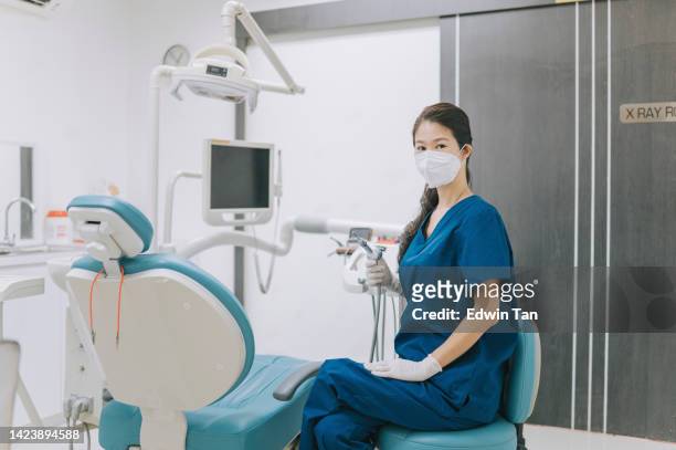 chinese female dentist looking at camera smiling in her office - orthodontist stock pictures, royalty-free photos & images
