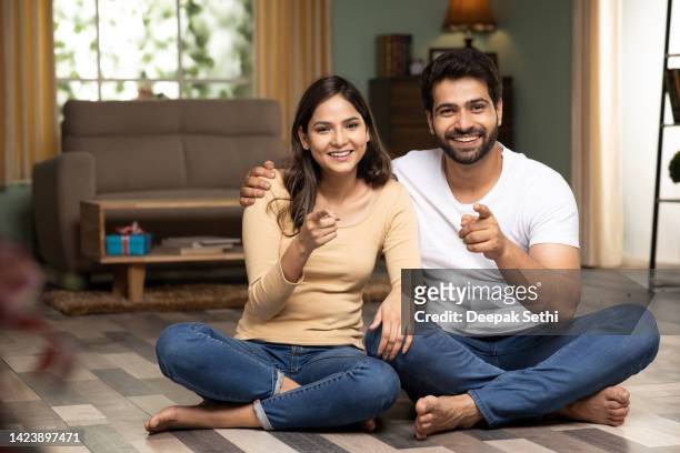 jovem casal sentado no chão, foto de estoque - pointing at camera - fotografias e filmes do acervo