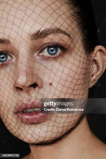 art photography of the beautiful woman with a black mesh on the face and a beautiful makeup on black background. the model is looking at camera. art concept of skin protection, skin care, cosmetics, beauty makeup, mental health. - blue lips stock pictures, royalty-free photos & images