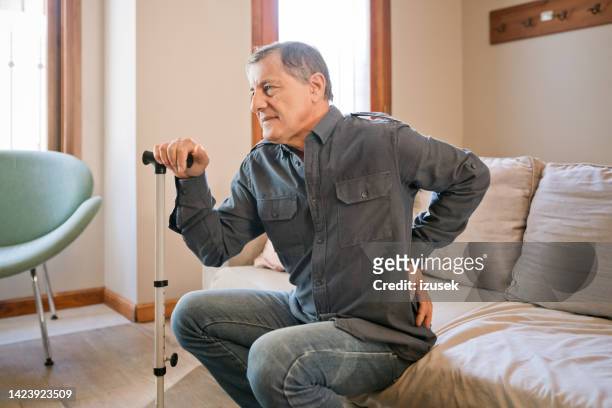 älterer mann mit rückenschmerzen zu hause - hip pain stock-fotos und bilder