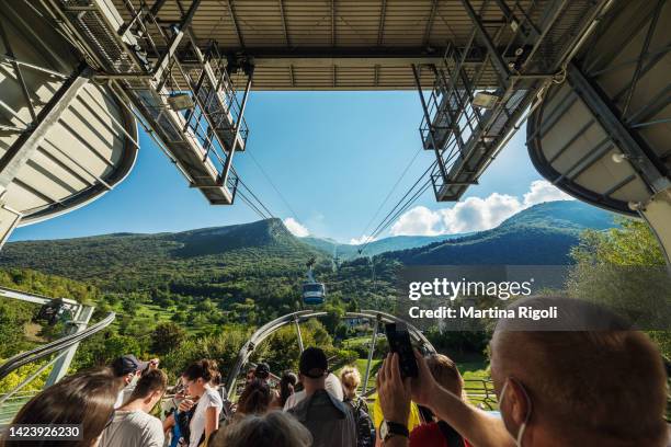 tourists waiting for the cable car to reach monte baldo from the station of san michele in malcesine - malcesine stock pictures, royalty-free photos & images
