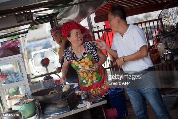 By Dan Martin This photograph taken on February 23, 2012 shows Soon Chuan Choo speaking with a customer as she prepares char kway teow in Georgetown,...