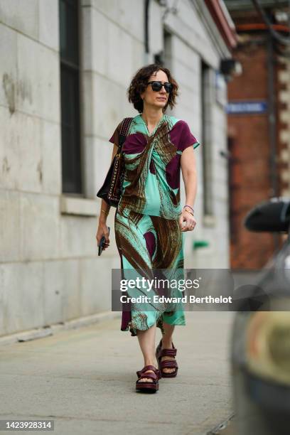 Guest wears black sunglasses, a mint green and purple print pattern short sleeves t-shirt, a matching mint green and purple print pattern midi skirt,...