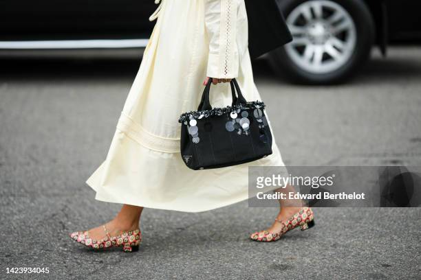 Guest wears a pale yellow long shirt, a black suede with embroidered large sequined handbag from Prada, pale red shiny leather with black and yellow...