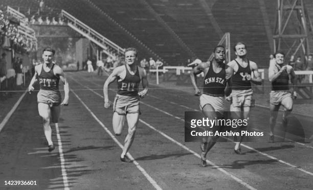 American athlete Barney Ewell , third from left, from Pennsylvania State University, breaks the tape at the finish line at an NCAA university...