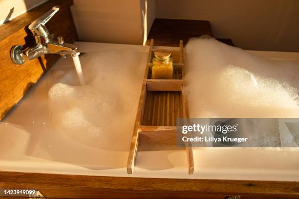 the bathtub with foam and bath salts in sunset light. - bath salt stock-fotos und bilder