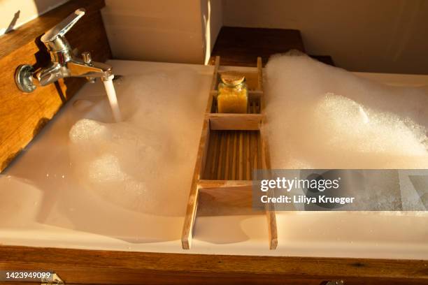 the bathtub with foam and bath salts in sunset light. - bath salt ストックフォトと画像