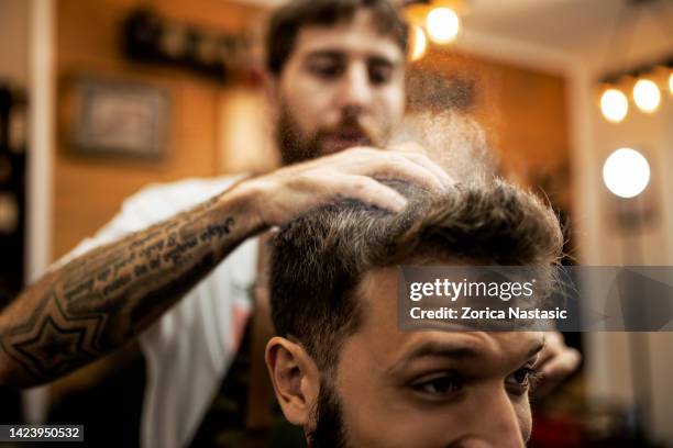 barber throwing talcum powder on the hair of a young man - dandruff stock pictures, royalty-free photos & images