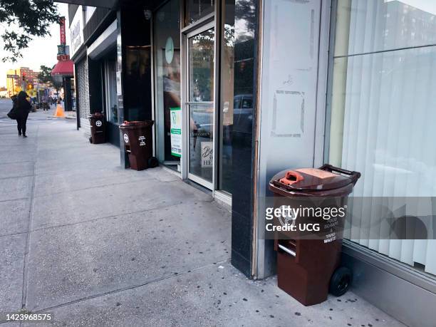 New Department of Sanitation food scraps and yard waste collection bins on sidewalks outside businesses, Queens, New York.