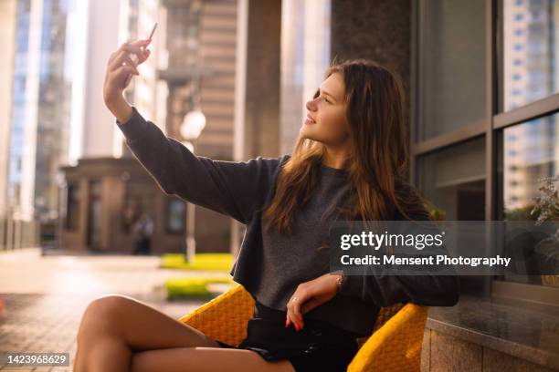 urban woman taking selfies her phone in sitting in a cafe - one finger selfie stock-fotos und bilder