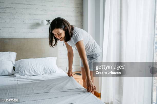 young woman making the bed in the morning - quarto arrumado imagens e fotografias de stock