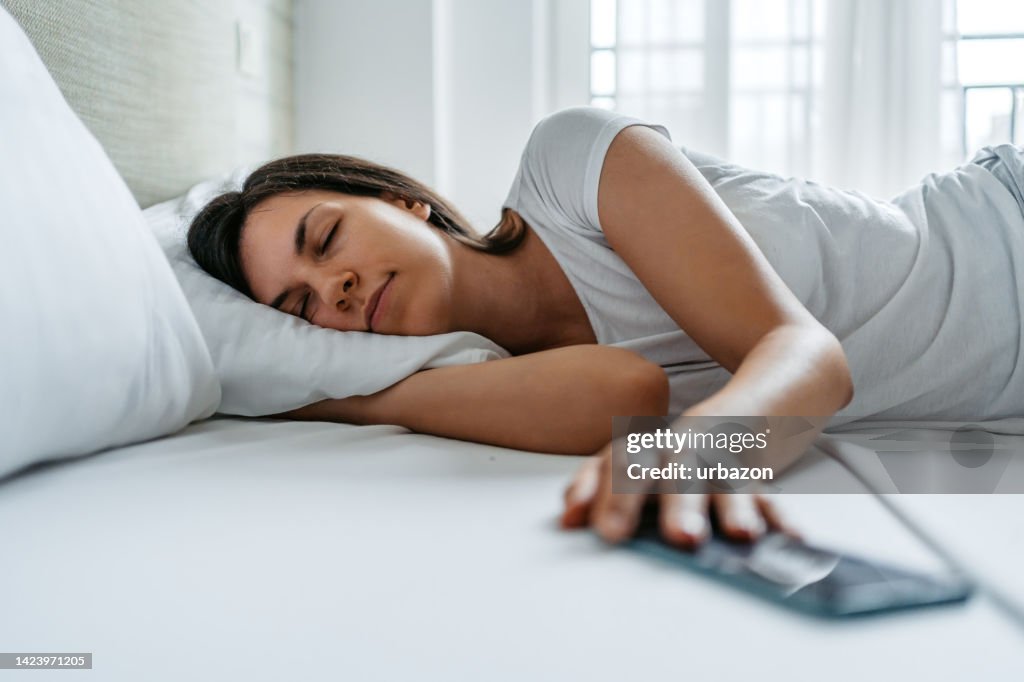 Young Woman Snoozing Her Alarm On A Smart Phone