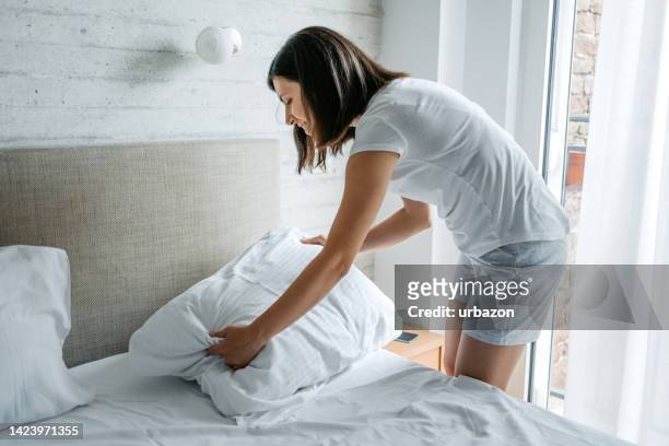 young woman making the bed in the morning - tidy bedroom stock pictures, royalty-free photos & images