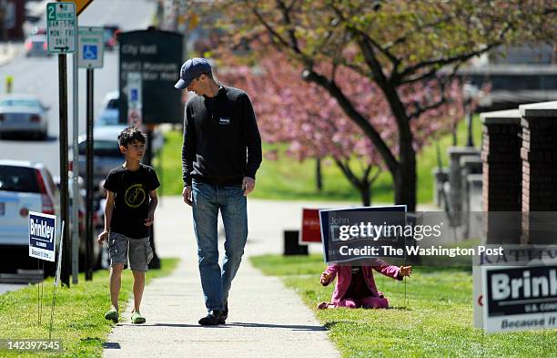 Jason Judd, of Frederick, Md. Walks with his son Mehta left, as his daughter Ruby adjusted a John Delaney campaign sign on his way to vote at the...