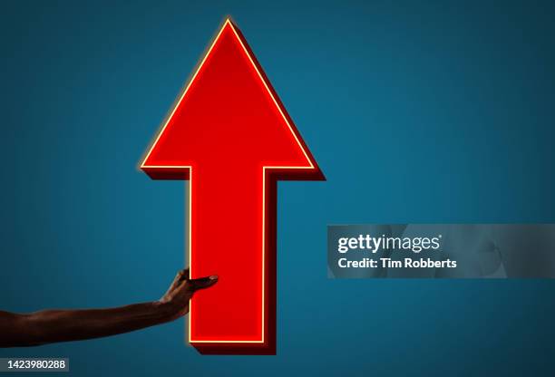 woman holding neon directional arrow - neon signs arrow stock pictures, royalty-free photos & images