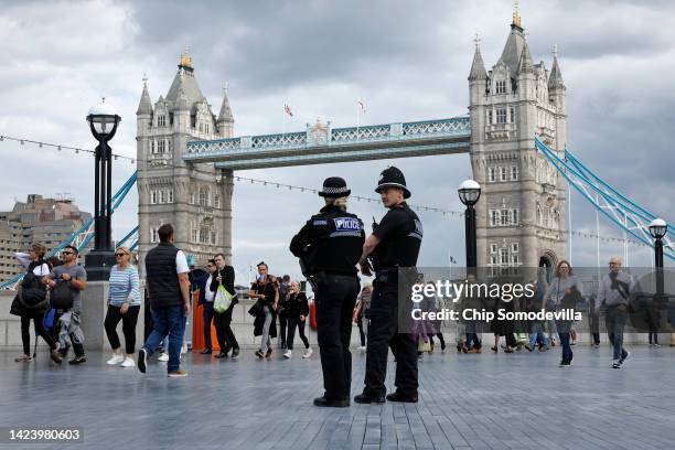 Two police officers stand as people walk in line along The Queens Walk near Tower Bridge as they march toward the public viewing of Queen Elizabeth...