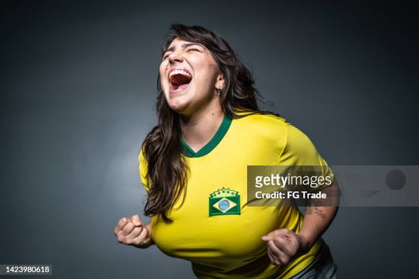 brasilianischer jungfan feiert auf gelber uniform - female fans brazil stock-fotos und bilder