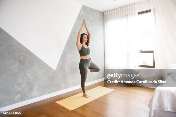 brazilian woman practicing yoga at her home - tree position stock pictures, royalty-free photos & images