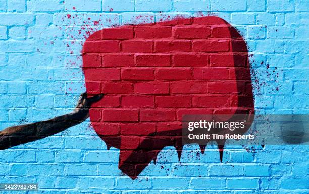 graffiti of arm holding speech bubble - graffiti wall stockfoto's en -beelden