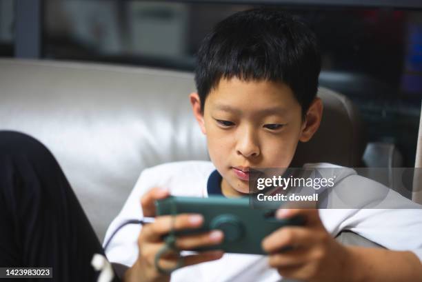 teenager play video game on mobile phone on sofa - movie china stockfoto's en -beelden