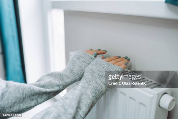 central heating problem at home. woman checking heating radiator in cold apartment - froid photos et images de collection