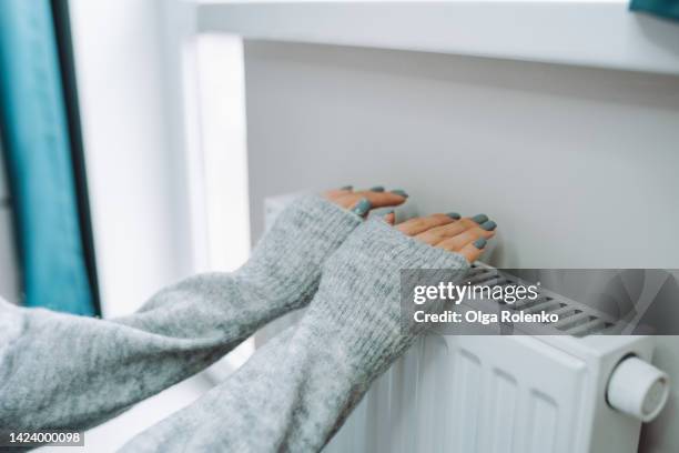 central heating problem at home. woman checking heating radiator in cold apartment - temperature 個照片及圖片檔