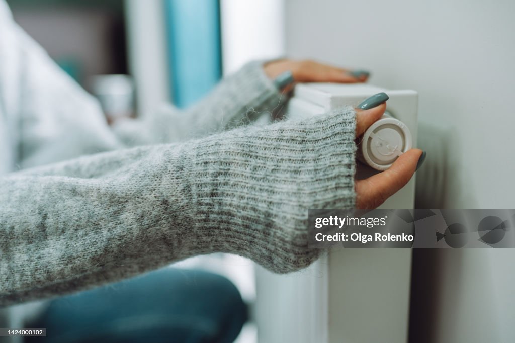 Heating control at home. Economic problem. Woman turn on, off heating radiator