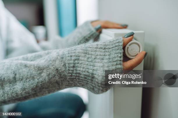 heating control at home. economic problem. woman turn on, off heating radiator - electric heater stock pictures, royalty-free photos & images