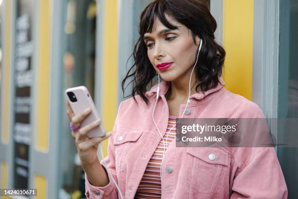 unusual looking young person using smart phone and consuming internet content on the go - non binary stereotypes stock pictures, royalty-free photos & images