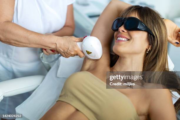 mittlere erwachsene frau genießt und entspannt sich, während sie schönheitsbehandlungen bekommt - laser stock-fotos und bilder