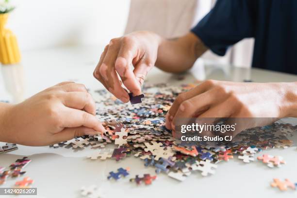 detail of hands looking for puzzle pieces - puzzel stockfoto's en -beelden