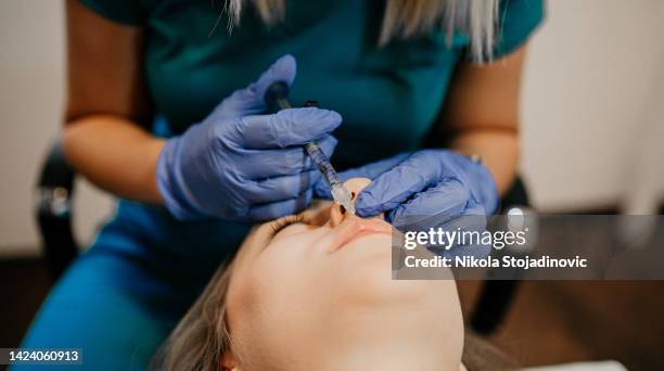 woman getting cosmetic injection of botulinum near lips - lip injections stockfoto's en -beelden