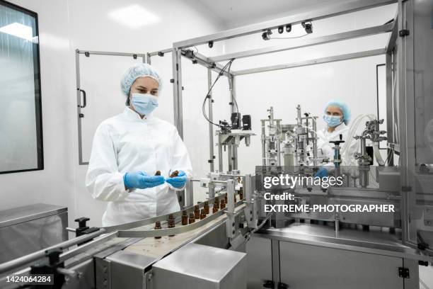 two fully equipped coworkers in protective workwear seen in a pharmaceutical laboratory - cleanroom stock pictures, royalty-free photos & images